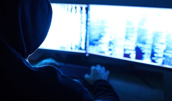 A hooded man uses a computer in this stock image.