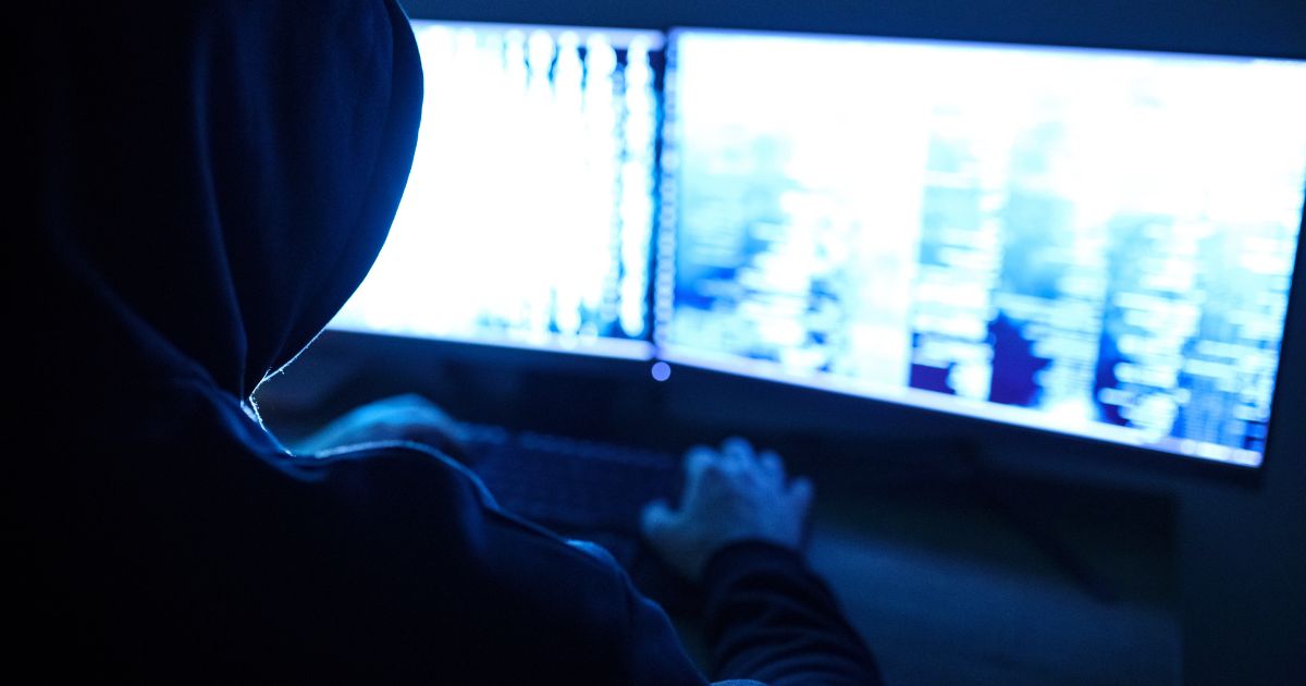 A hooded man uses a computer in this stock image.