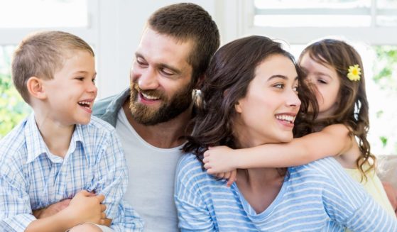 A stock photo shows a couple and their children playing together on the sofa.