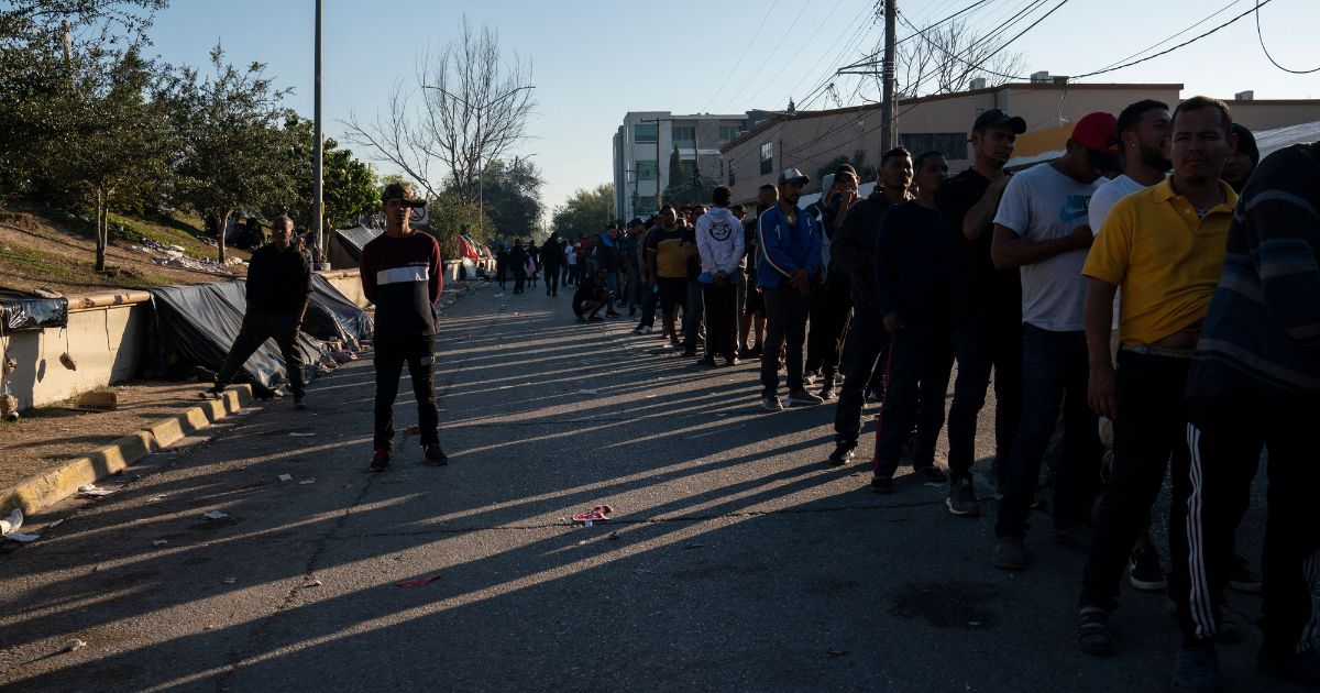 Migrants who are waiting to seek asylum in the United States wait in line to write their names down on a list to potentially be called for processing, in Matamoros, Tamaulipas, Mexico, on December 22, 2022.