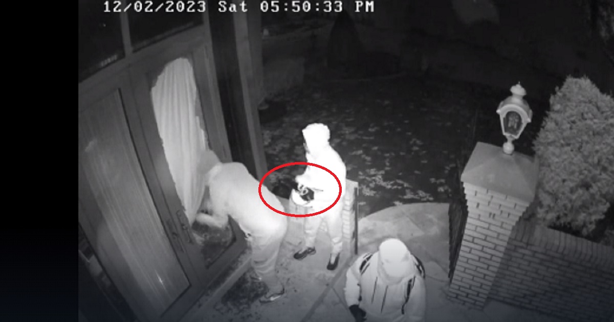 A still from a surveillance video shows a gang breaking into a home -- with one of the men holding a jammer.