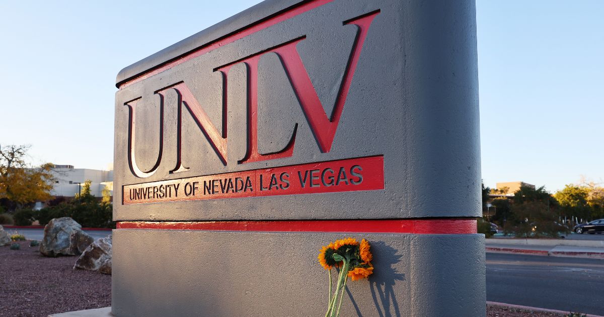 Flowers rest against a UNLV campus sign after a December 6 shooting left three dead at the University of Nevada, Las Vegas campus on December 7, 2023 in Las Vegas, Nevada.
