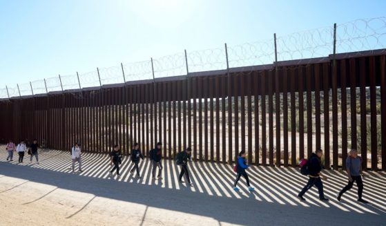 A group of people walk along the wall after crossing the border with Mexico on Oct. 24 near Jacumba, California.