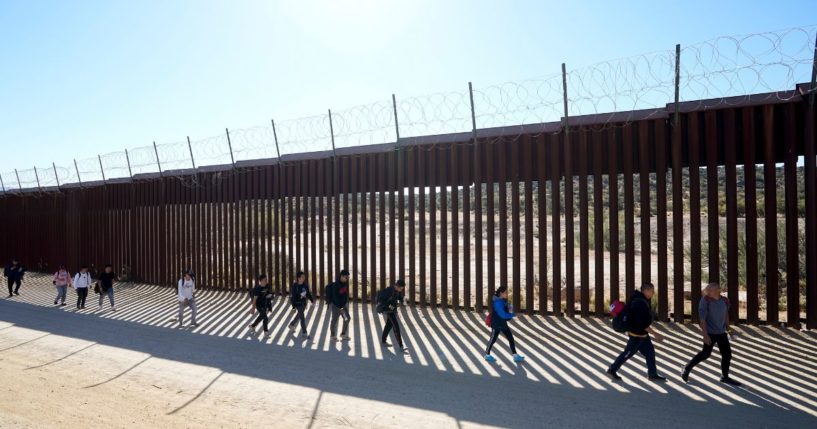 A group of people walk along the wall after crossing the border with Mexico on Oct. 24 near Jacumba, California.
