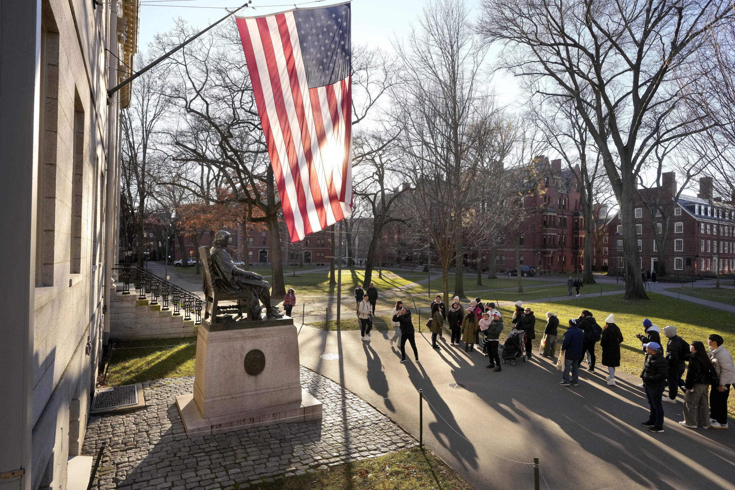 People take photos near a John Harvard statue, left, on the Harvard University campus in Cambridge, Massachusetts, on Jan. 2.