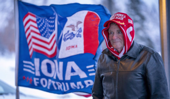 A man stands next to a flag that reads "Iowa for Trump" outside the Machine Shed in Urbandale, Iowa, on Thursday.