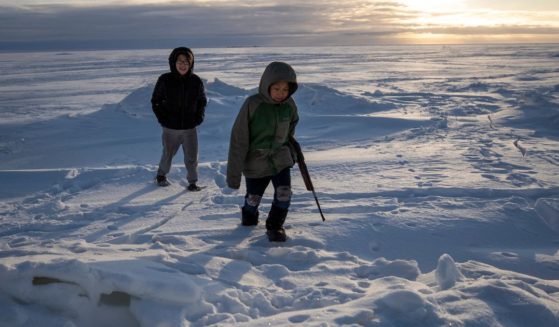 Alaska residents George Chakuchin, left, and Mick Chakuchin walk in the snow with a rifle near Toksook Bay, Alaska, Jan. 18, 2020.