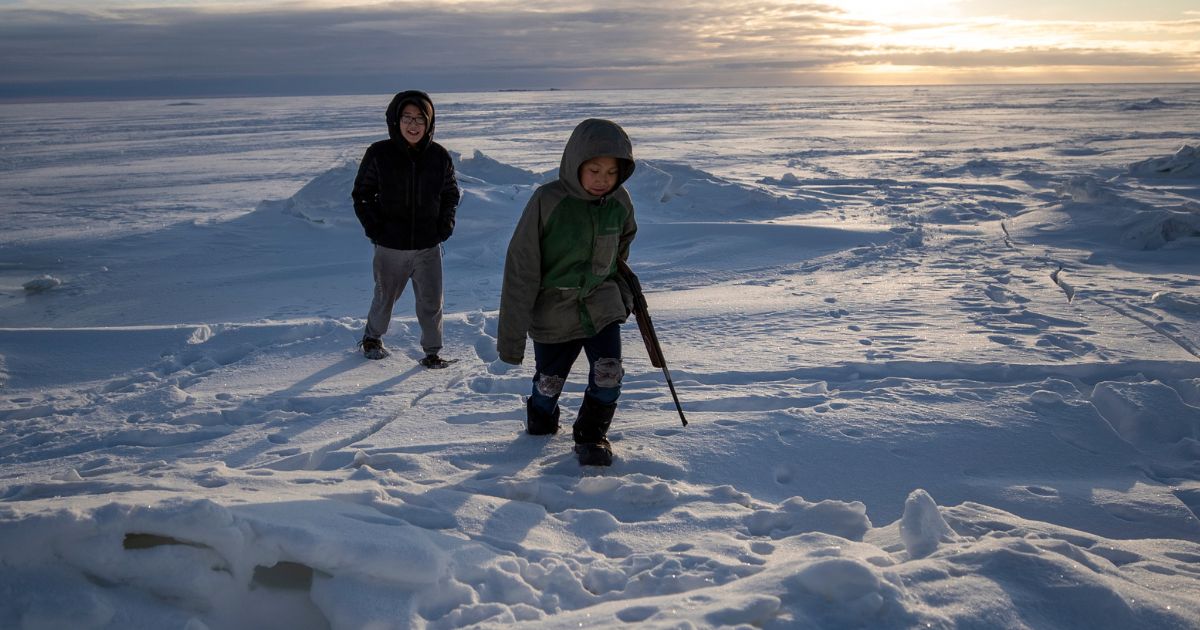 Alaska residents George Chakuchin, left, and Mick Chakuchin walk in the snow with a rifle near Toksook Bay, Alaska, Jan. 18, 2020.