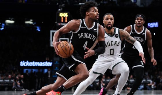 Dennis Smith Jr. of the Brooklyn Nets is defended by Damian Lillard of the Milwaukee Bucks during the third quarter of a game at Barclays Center on Dec. 27, 2023, in New York City.
