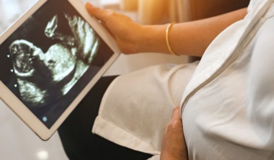 In this stock image a pregnant woman holds a tablet displaying an ultrasound.
