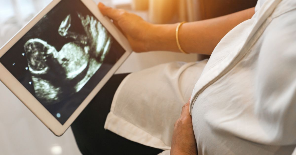 In this stock image a pregnant woman holds a tablet displaying an ultrasound.