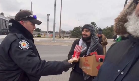 A Toronto police officer delivers coffee to anti-Israel protesters.