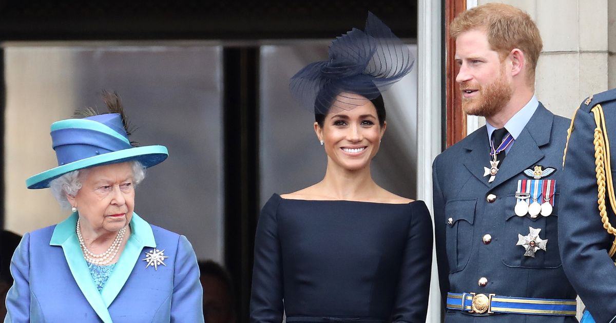 Queen Elizabeth II, Meghan, Duchess of Sussex, and Prince Harry, Duke of Sussex, look on from the balcony of Buckingham Palace in London as the royal family marks the centenary of the RAF on July 10, 2018.