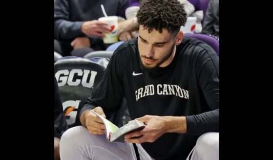 Gabe McGlothan of the Grand Canyon University Antelopes reads the Bible on the bench before games.