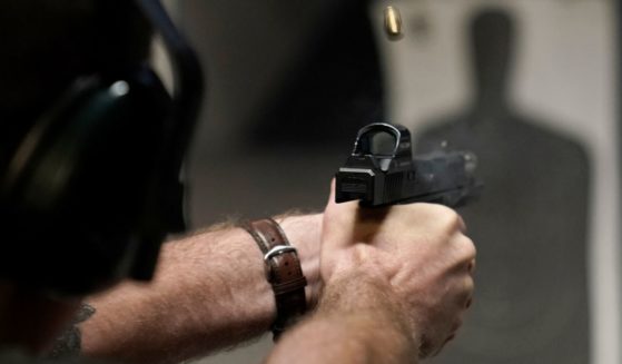 A man fires his pistol at an indoor shooting range in Roseville, California.