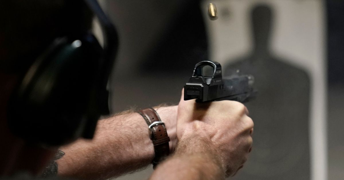 A man fires his pistol at an indoor shooting range in Roseville, California.