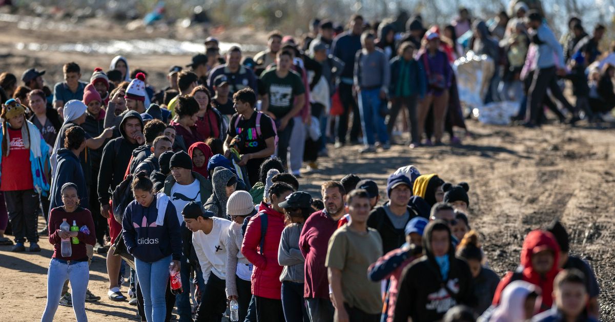 More than 1,000 illegal immigrants wait in line to be processed by U.S. Border Patrol agents after crossing the Rio Grande from Mexico into Eagle Pass, Texas, on Dec. 18.