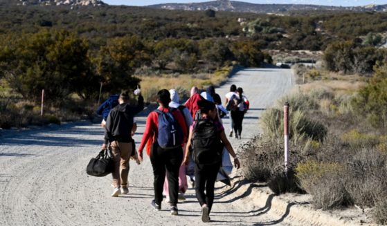 Asylum seekers walk to a U.S. Border Patrol van after crossing the border with Mexico, near Jacumba Hot Springs, California.