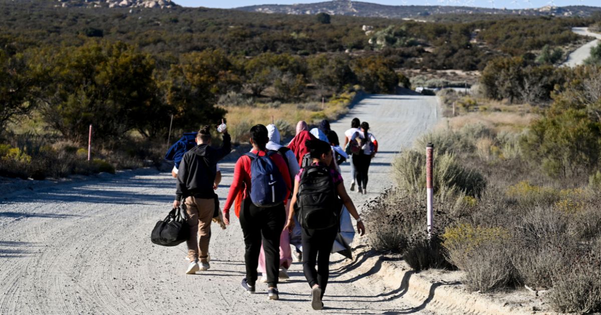 Asylum seekers walk to a U.S. Border Patrol van after crossing the border with Mexico, near Jacumba Hot Springs, California.