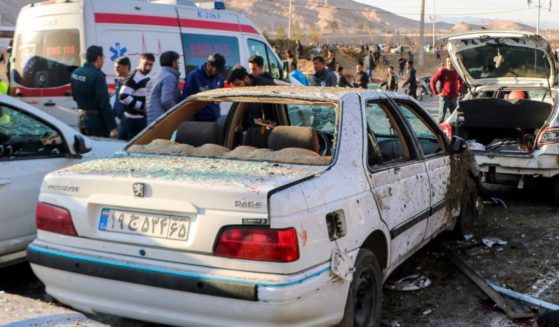 destroyed cars and emergency services near the site where two explosions struck a crowd in Iran