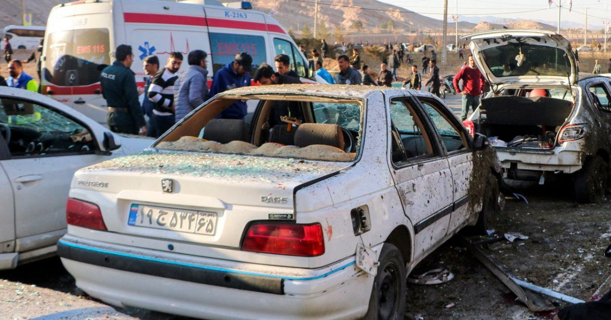 destroyed cars and emergency services near the site where two explosions struck a crowd in Iran