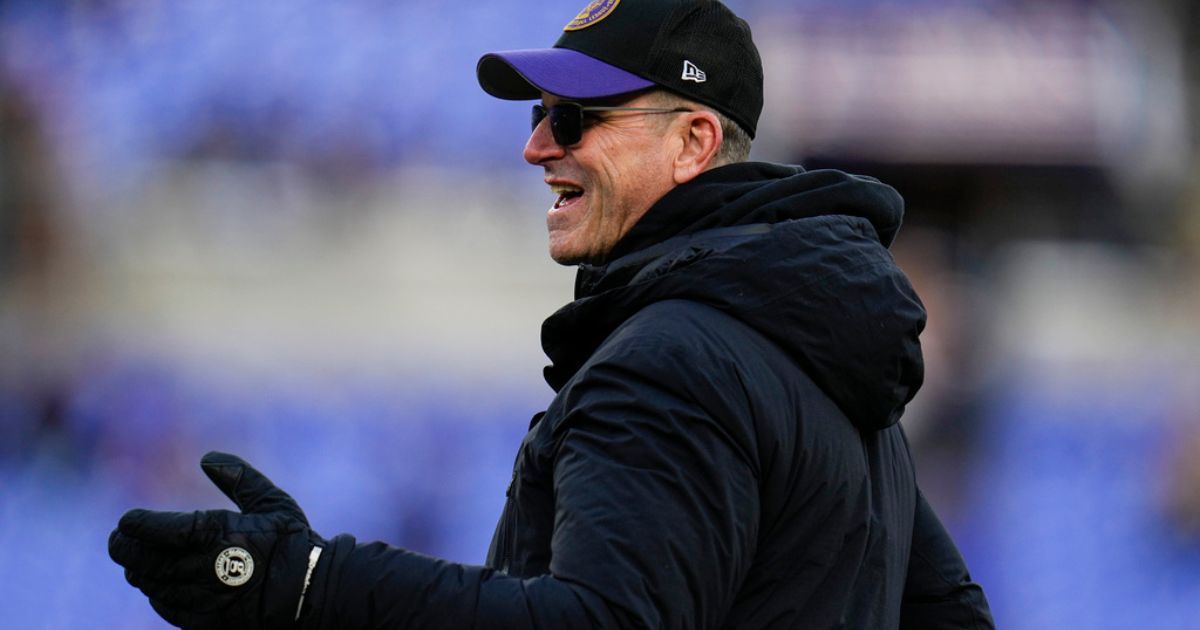 Michigan head coach Jim Harbaugh walks the field before Saturday's NFL football AFC divisional playoff game between the Baltimore Ravens and the Houston Texans in Baltimore.