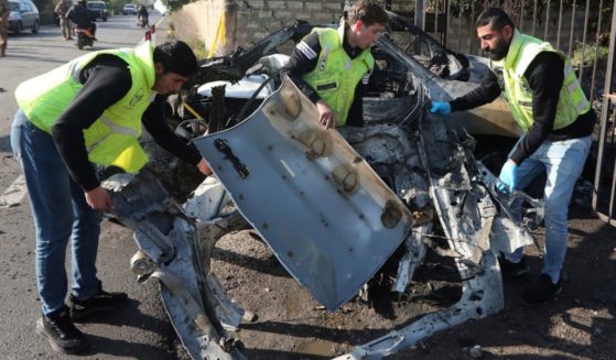 Civil defense workers remove parts of a destroyed car in the southern town of Bazouriyeh, Lebanon, Saturday. An Israeli drone strike on the car near the Lebanese southern port city of Tyre killed two people, the state-run National News Agency reported.
