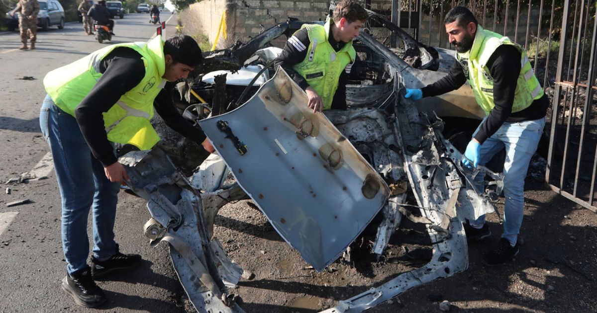 Civil defense workers remove parts of a destroyed car in the southern town of Bazouriyeh, Lebanon, Saturday. An Israeli drone strike on the car near the Lebanese southern port city of Tyre killed two people, the state-run National News Agency reported.
