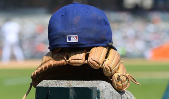 The MLB logo is pictured on the back of a Texas Rangers baseball cap sitting on top of a baseball glove in the dugout during the game against the Detroit Tigers in Detroit, Michigan, on May 29.