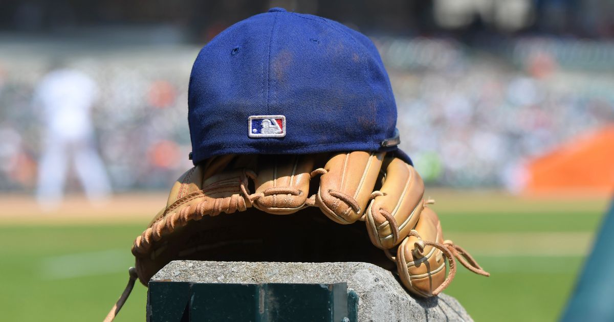 The MLB logo is pictured on the back of a Texas Rangers baseball cap sitting on top of a baseball glove in the dugout during the game against the Detroit Tigers in Detroit, Michigan, on May 29.