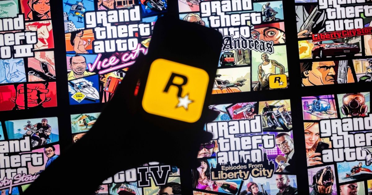 The logo of Rockstar Games on a smart phone in front of the covers of various Grand Theft Auto games.