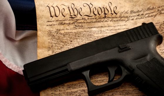 A handgun is pictured with an American flag and the U.S. Constitution in this stock photo.