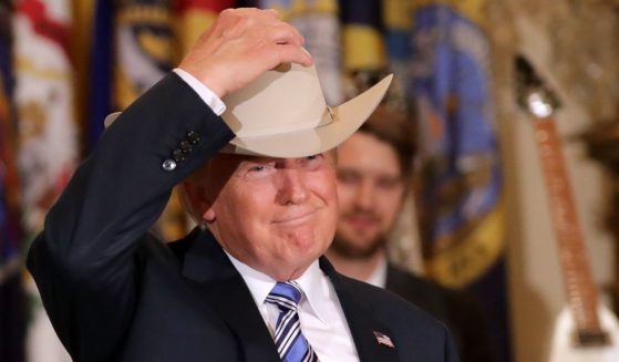 Then-President Donald Trump puts on a Stetson cowboy hat while touring a Made in America product showcase in the East Room of the White House in Washington on July 17, 2017.