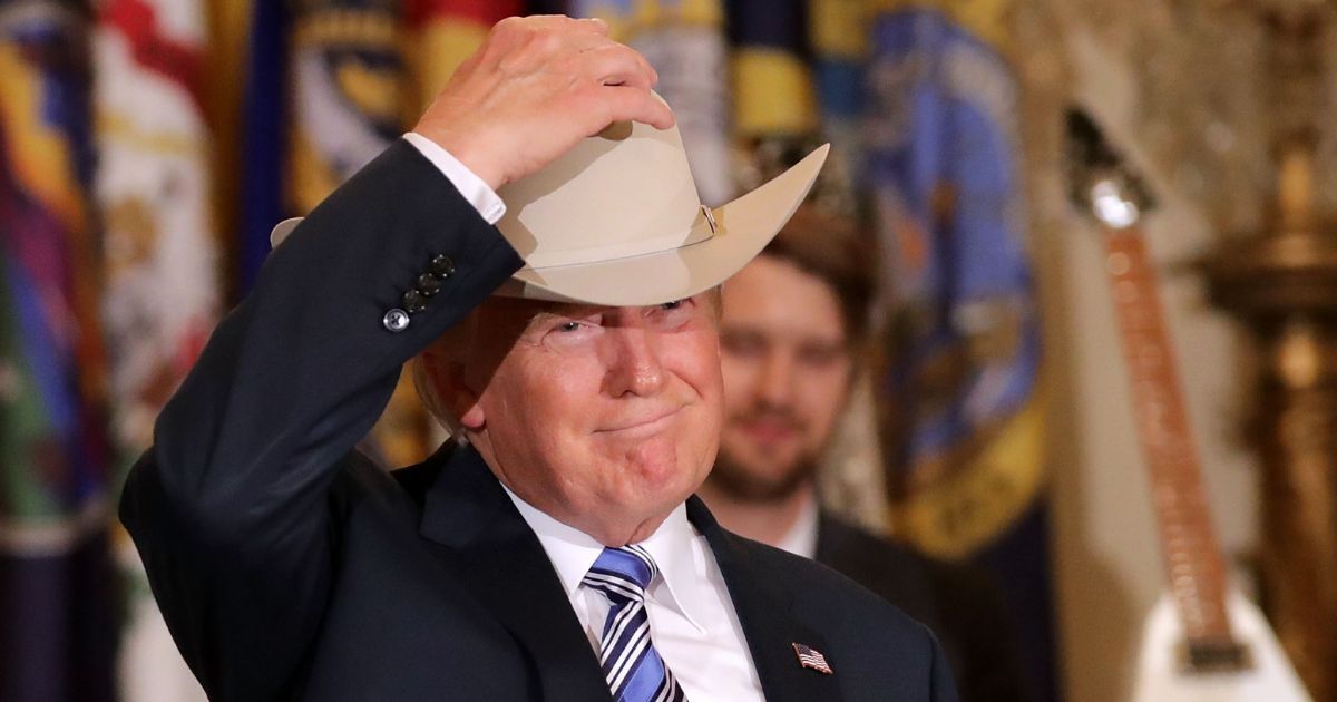 Then-President Donald Trump puts on a Stetson cowboy hat while touring a Made in America product showcase in the East Room of the White House in Washington on July 17, 2017.