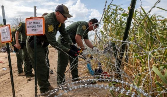 Border Patrol agents cut an opening through razor wire after immigrant families crossed the Rio Grande from Mexico, September 27, in Eagle Pass, Texas.