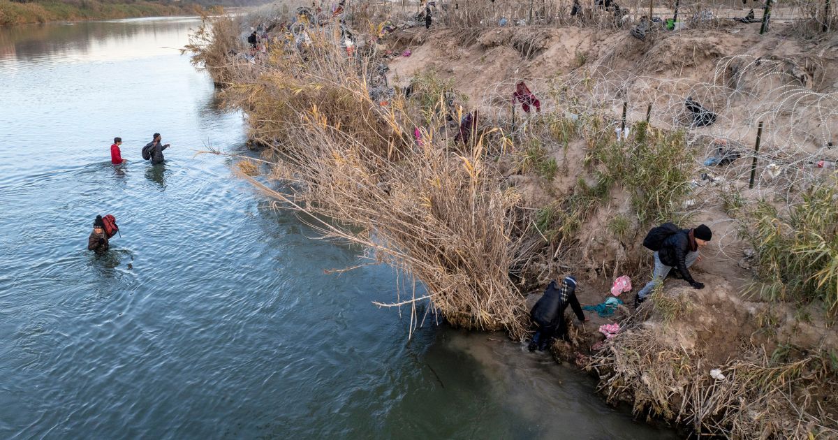 Immigrants climb up the bank of the Rio Grande while crossing from Mexico into the United States near Eagle Pass, Texas, on Jan. 7.