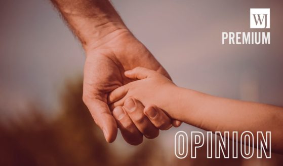 A father holds his child's hand in this stock image.