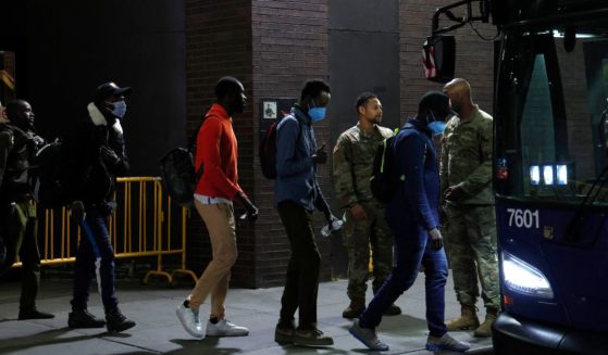 U.S. military personnel keep watch as asylum seekers are transferred via city bus from Port Authority bus terminal to housing facilities in the Bronx and Queens on May 15 in New York City.