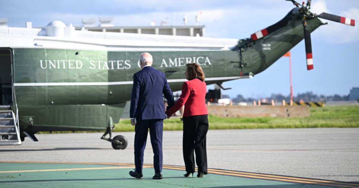 President Joe Biden walks hand-in-hand with Rep. Nancy Pelosi at San Francisco International Airport in California on Wednesday.