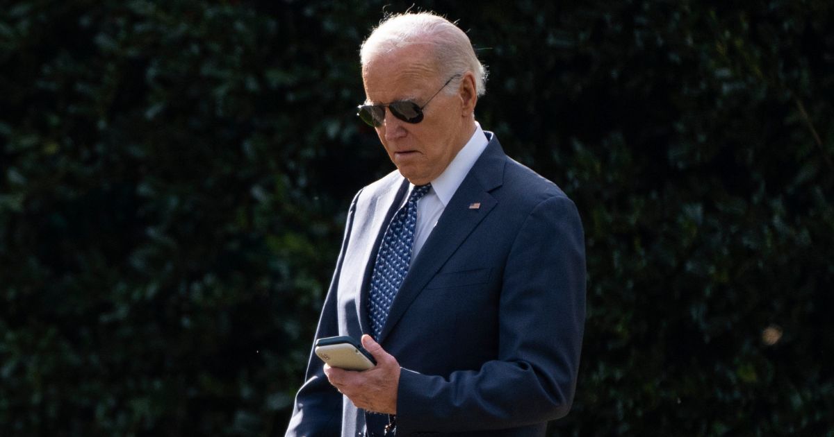 President Joe Biden looks at his phone as he walks to board Marine One on the South Lawn of the White House in Washington on Feb. 8.