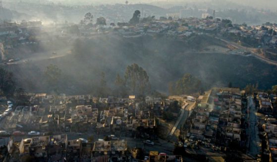 Smoke raises from burned-out houses Saturday after a forest fire reached the Villa Independencia neighborhood in Vina del Mar, Chile.
