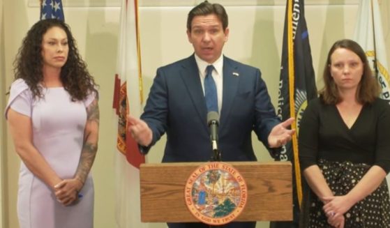 Florida Gov. Ron DeSantis is flanked by two of the late Jeffery Epstein's victims, Haley Robson, left, and Jena-Lisa Jones, after signing a bill Thursday into law that officially authorizes the release of documents from a grand jury investigation in Palm Beach County regarding Epstein's sexual assault of underage girls.