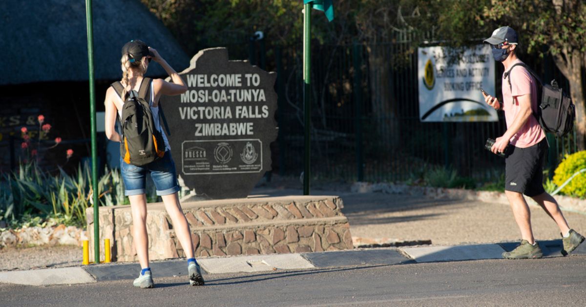 Tourists stand at the entrance to Zimbabwe’s Victoria Falls National Park, in August 2021.