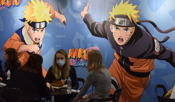 A large "Naruto" poster displayed behind groups of people discussing business at 2021's ExCel in London.