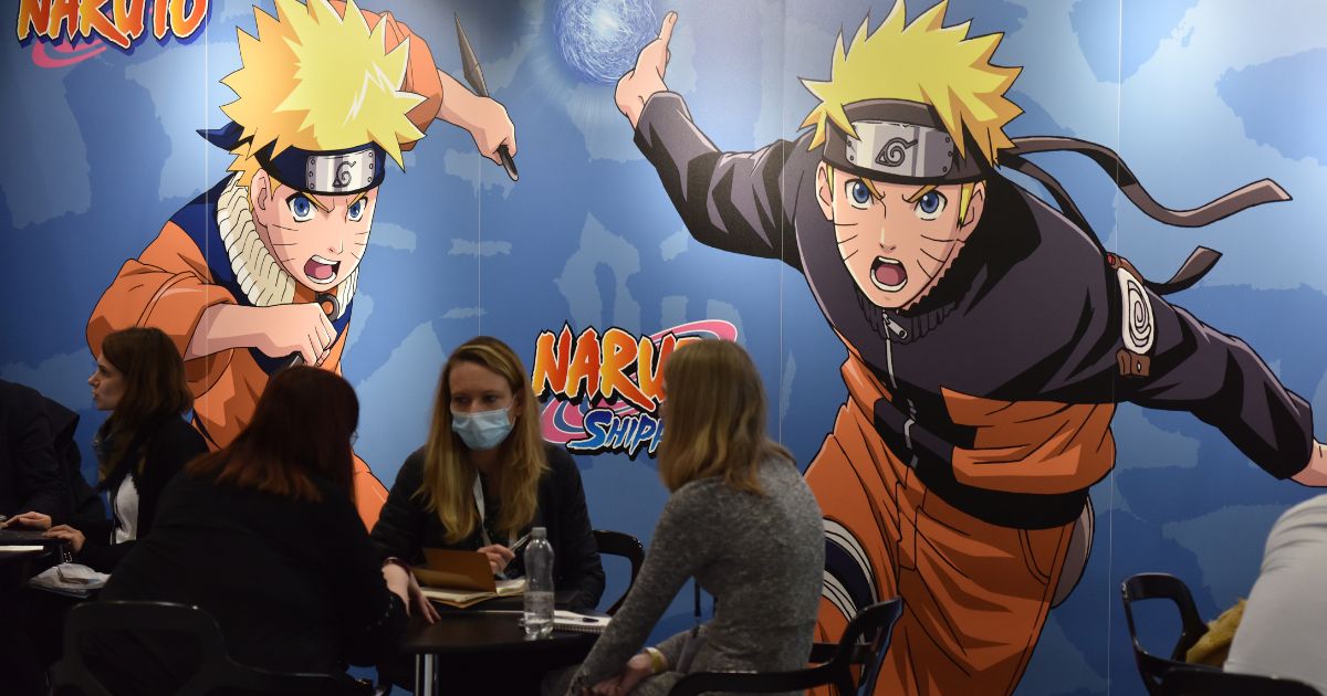 A large "Naruto" poster displayed behind groups of people discussing business at 2021's ExCel in London.