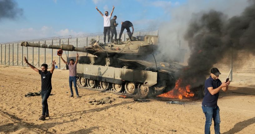 Palestinians celebrate by a destroyed Israeli tank at the Gaza Strip fence east of Khan Younis on Oct. 7.