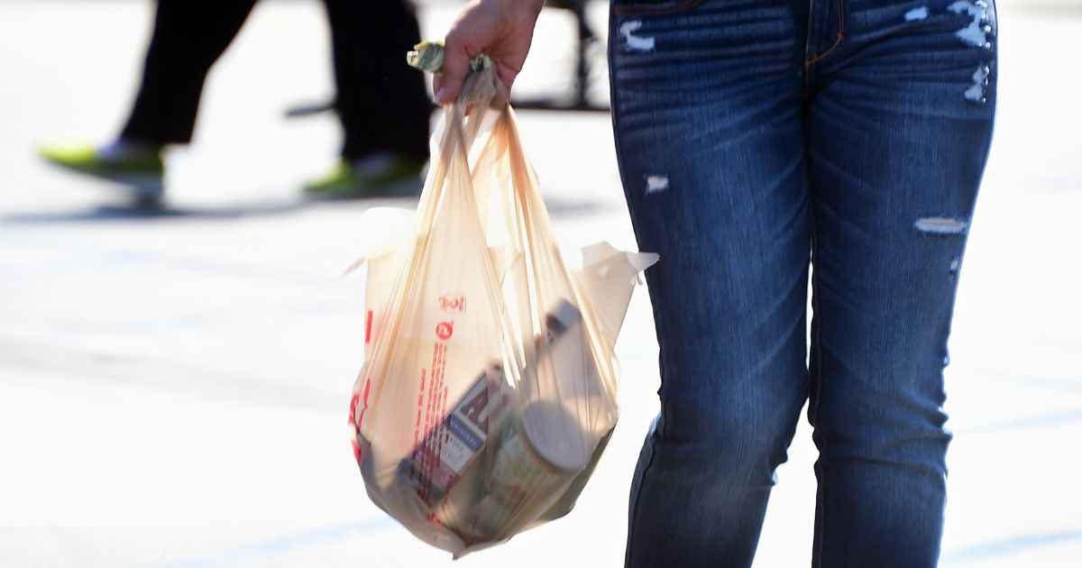 A woman carries her groceries in a plastic bag while leaving a supermarket in Monterey Park, California, on Sept. 30, 2014, right after the state's governor signed the country's first statewide ban on single-use plastic bags from convenience and grocery stores. The ban went into effect in July 2015.