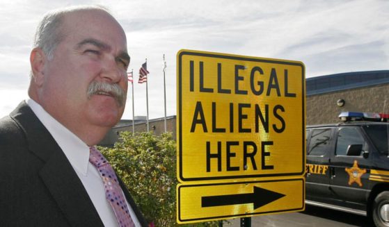 Butler County, Ohio, Sheriff Richard Jones stands next to a sign with an arrow labeled "Illegal Aliens Here" that he had installed in the sheriff's office parking lot in Hamilton, Ohio.