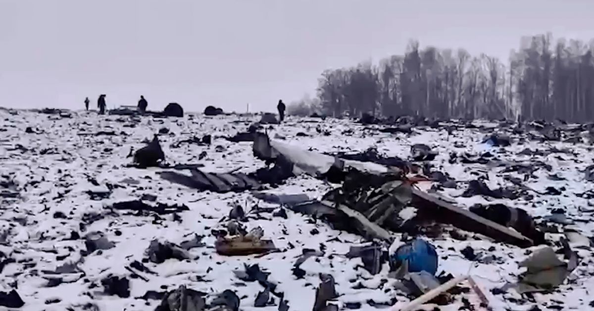 Russian Investigative Committee employees walking near wreckage of a Russian military Il-76 plane