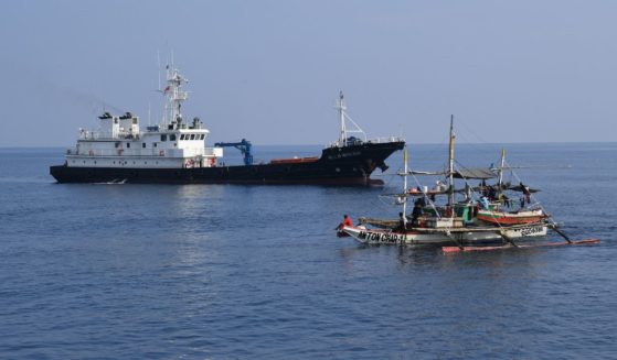 A Philippine fishing boat sails past a Chinese militia ship near the Scarborough Shoal in the disputed South China Sea on Sept. 20.